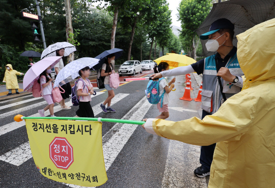 8월 28일 오전 서울 양천구의 한 초등학교 앞에서 서울시, 경찰 관계자 등이 학교 개학을 맞아 어린이들의 안전한 등교를 위한 안내를 하고 있다.  <연합뉴스>